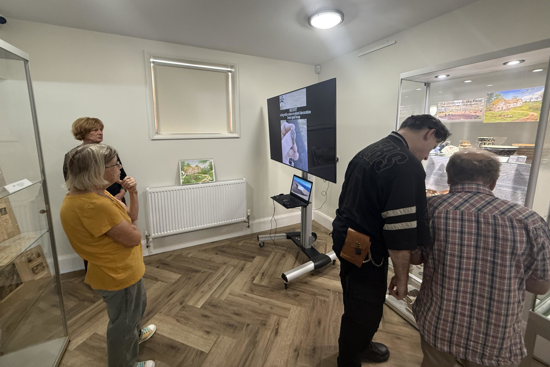 As part of the exhibition, Helen Malbon had produced a short video using Dave Thomas' site videos, pictures and 3d re-constructions, as an introduction to the excavation, With Angela and Carol checkig all is ok. The TV is set up next to the display case at the Heritage Centre where the Society currently has a display-unfortunately Jase and Alan are standing in front of it!