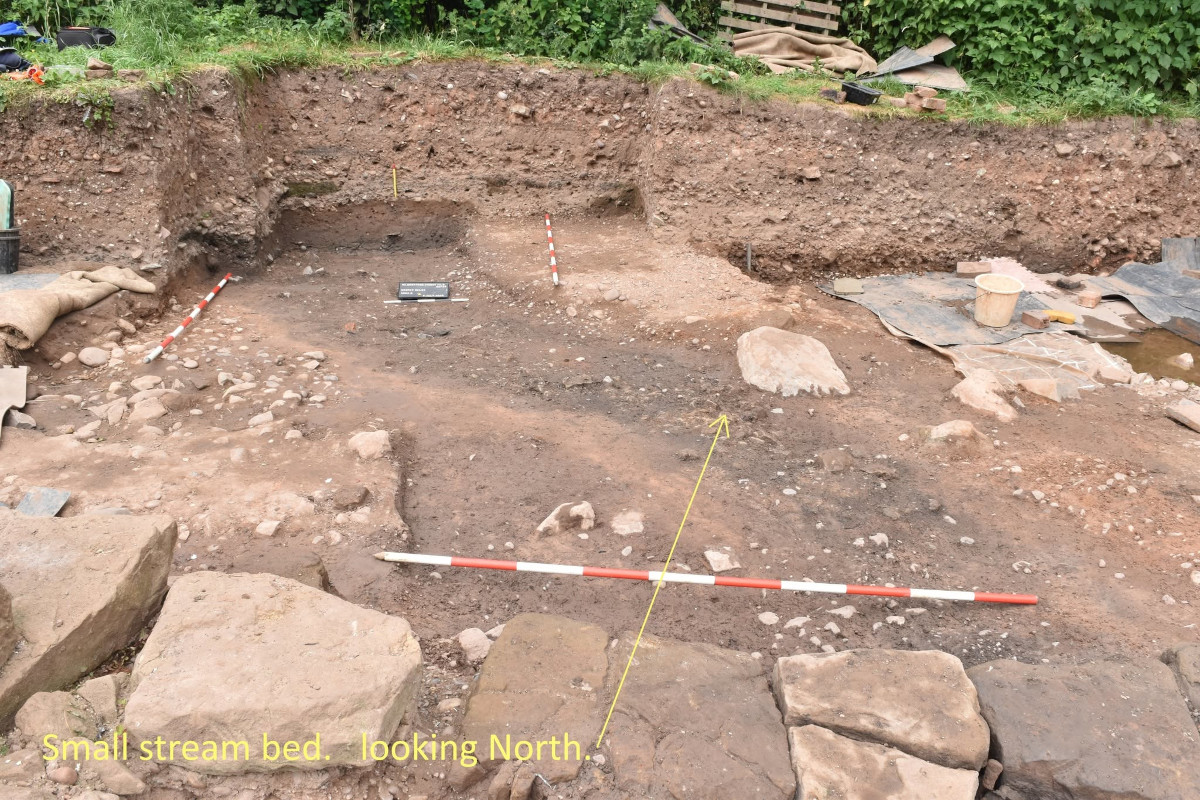 The stream bed of a small stream that appears run under the East Wing of the building towards the present stream just out of sight beyond the bushes at the top of the image